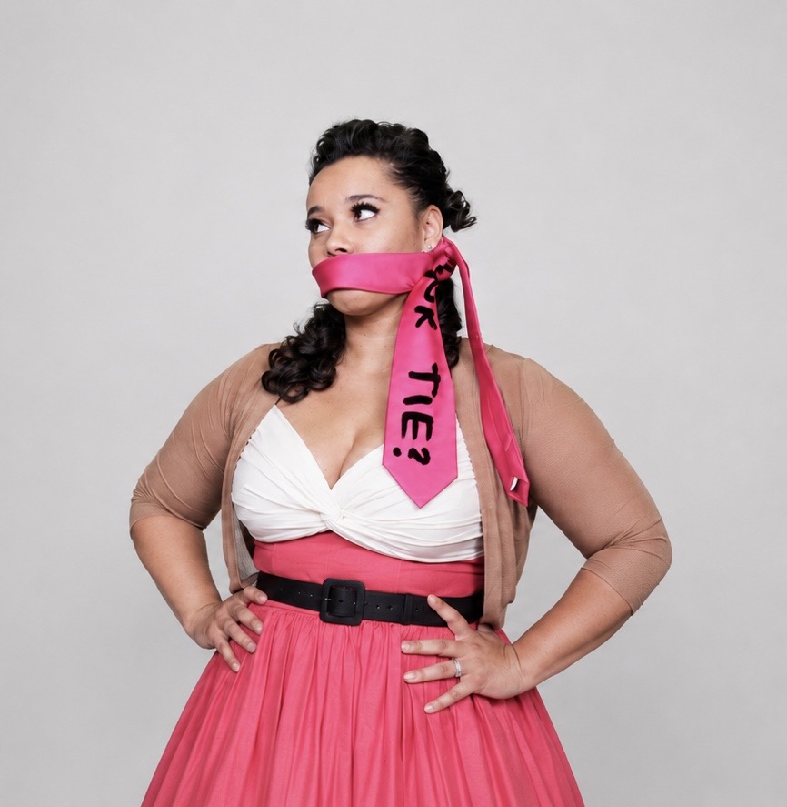 Veronica gagged with a pink tie that reads Pink Tie Magic